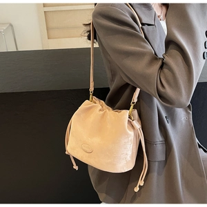 Detailed side view of apricot matte suede drawstring bucket bag with leather brand logo