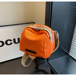 Detail view of bright orange canvas shell bag with ethnic bohemian embroidered wide strap