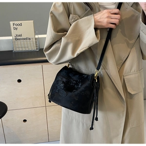 Detail of vintage black bucket bag showing the unique texture and gold hardware on a strap