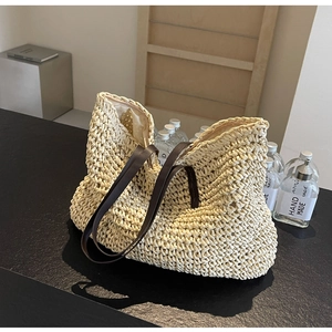 Detail of hand-woven straw tote bag with brown leather handles and zipper closure