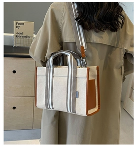 Vue détaillée du sac cabas en toile avec garniture cuir marron et bandoulière rayée