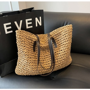 Detailed view of woven straw tote bag texture with brown leather handles and stitching