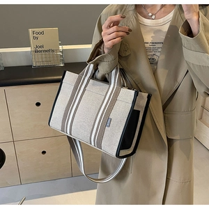 Détail d'un sac cabas en toile avec garniture en cuir noir et poignées tissées rayées