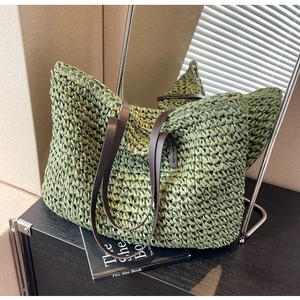 Detail of green straw tote bag featuring woven texture and brown leather handles