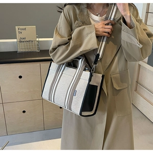 Modèle portant un sac fourre-tout en toile avec bandoulière rayée en décor moderne