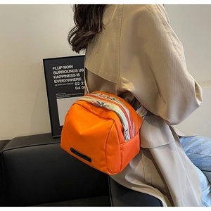 Detail of bright orange nylon crossbody bag with ethnic style embroidered wide strap