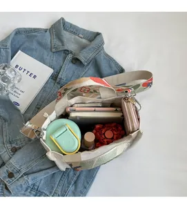 Geräumiges Tascheninnere der Canvas-Beuteltasche mit floralem Gurt und Alltagsgegenständen