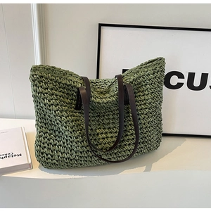 Detail of green straw woven tote bag featuring dark brown leather handles and rich texture