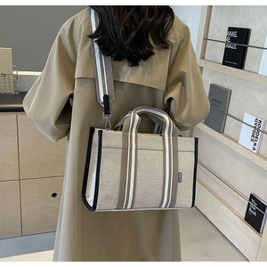 Vue détaillée d'un sac cabas en toile avec sangles rayées porté par un mannequin