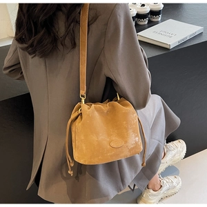 Brown frosted leather bucket bag with drawstring closure shown in a lifestyle scene