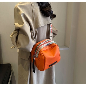 Detail of bright orange crossbody shell bag with ethnic floral embroidered wide strap
