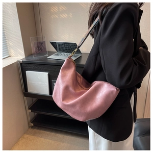 Detail of pink hobo bag featuring a wide retro woven strap and soft textured leather