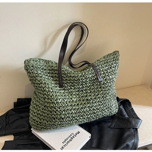Detail of green straw tote bag with brown leather handles and woven texture details