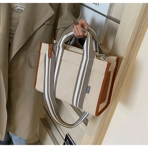 Détail d'un sac cabas en toile avec garniture en cuir brun et sangle en tissu rayé
