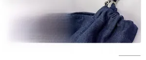 Détail du tissu denim bleu marine avec double couture renforcée et boucle de chaîne en métal