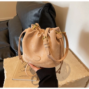 Detail of beige drawstring bucket bag with gold hardware and vintage matte texture