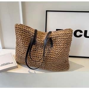 Close-up of hand-woven straw tote bag texture and dark brown leather shoulder straps