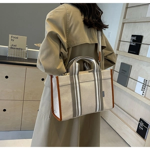 Détail du sac cabas en toile avec garniture en cuir marron et bandoulière rayée vue de dos