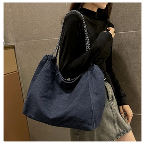 Vue détaillée du sac cabas en denim bleu foncé avec une chaîne en métal et cuir
