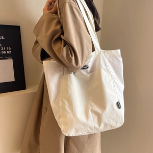 Minimalist white canvas tote bag with black logo patch for women's casual daily commute