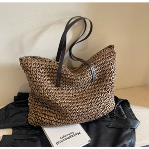 Detailed close-up of dark brown hand-woven straw tote bag with premium leather straps