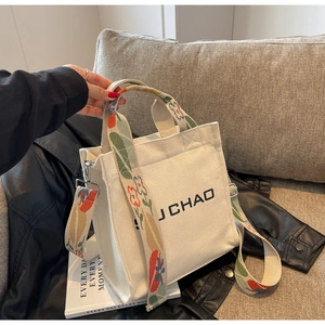 Detailansicht der cremefarbenen Canvas-Tasche mit floralem Gurt und J CHAO Logo-Aufdruck