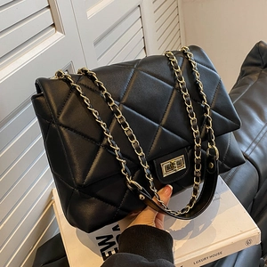 Classic black quilted shoulder bag with gold chain strap and turn-lock closure on white book