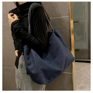 Grand sac cabas en denim avec bandoulières en chaîne argentée porté par un mannequin