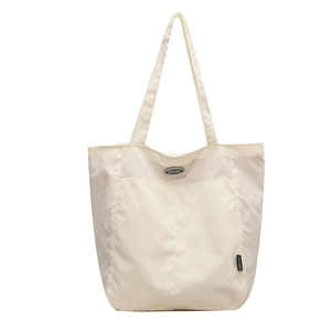 Cream canvas tote bag with DOUGU logo patch and wide shoulder straps on white background