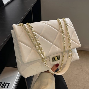 White quilted flap chain bag with gold metal hardware shown in a minimalist setting