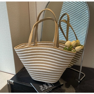 Detail der gewebten Khaki-weiß gestreiften Shopper-Tasche mit Fokus auf Textur und Griffe