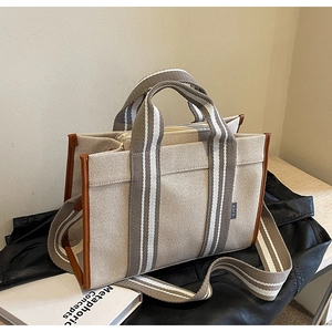 Détail du cabas en toile beige avec garniture en cuir brun et sangle rayée sur veste en cuir