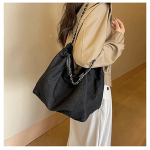 Détail du grand sac cabas en jean noir avec sangle en chaîne et design plissé chic
