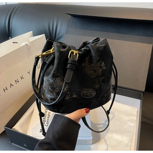 Detail of vintage black matte bucket bag with drawstring closure and gold metal hardware