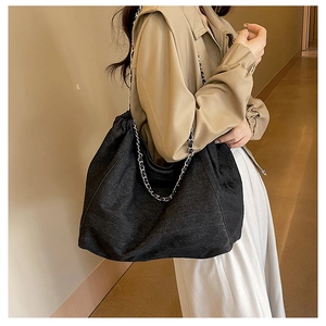 Détail du grand sac cabas en denim noir avec chaîne argentée et fermeture plissée