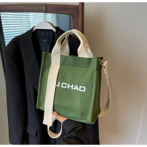Detail der grünen Canvas-Beuteltasche mit weißen Baumwollgurten und J CHAO Aufdruck