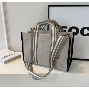 Détail du sac cabas en toile beige avec garniture en cuir noir et sangle rayée