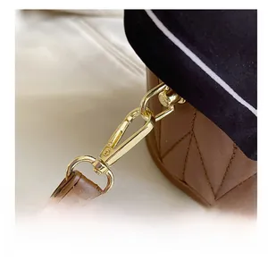 Detailed close-up of golden metal clasp on brown quilted leather bucket bag with strap