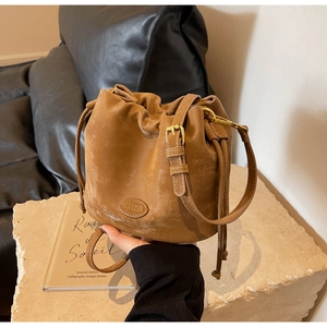 Close-up of retro brown frosted leather bucket bag with drawstring and metal buckle
