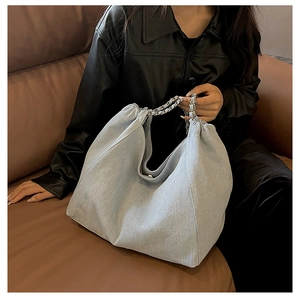 Détail du grand sac cabas en denim bleu clair avec chaîne argentée et plis style hobo