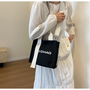 Seitenansicht der schwarzen Canvas-Beuteltasche mit U CHAO Print und weißem Schultergurt