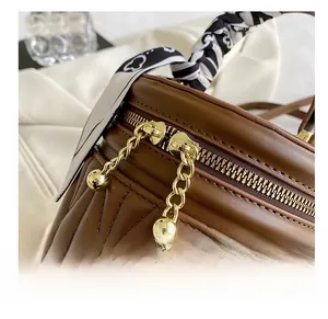 Detail of dark brown bucket bag featuring quilted texture and golden camellia charm