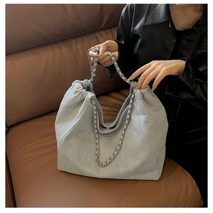 Détail du sac cabas en denim bleu clair avec fermeture à cordon et chaîne argentée
