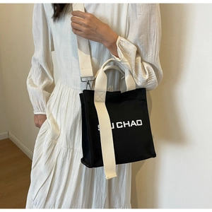 Detailansicht schwarze Canvas-Beuteltasche mit breitem Baumwollriemen und weißem Logo