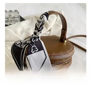 Macro shot of brown quilted bucket bag with silk scarf handle and gold chain zippers