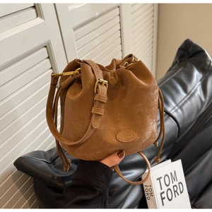 Close-up of vintage brown matte bucket bag showing drawstring closure and brand plaque