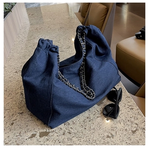 Détail du sac cabas en denim bleu foncé avec bandoulière chaîne et cordon serrage