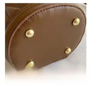 Detail shot of mini bucket bag bottom with four gold protective metal feet and fine stitching