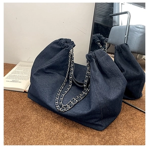 Détail du grand sac cabas en jean avec bandoulière chaîne et cordon sur tapis brun