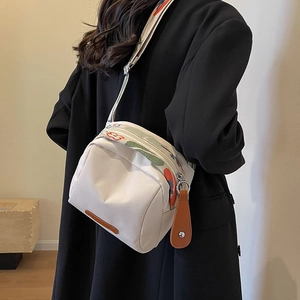 White canvas crossbody shell bag with colorful jacquard strap and leather trim detail